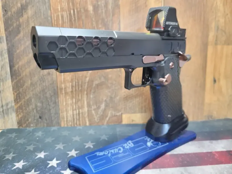 Custom 2011 with hex-cut slide, bronze controls, and Vortex red dot — left profile on D2 Customs display stand