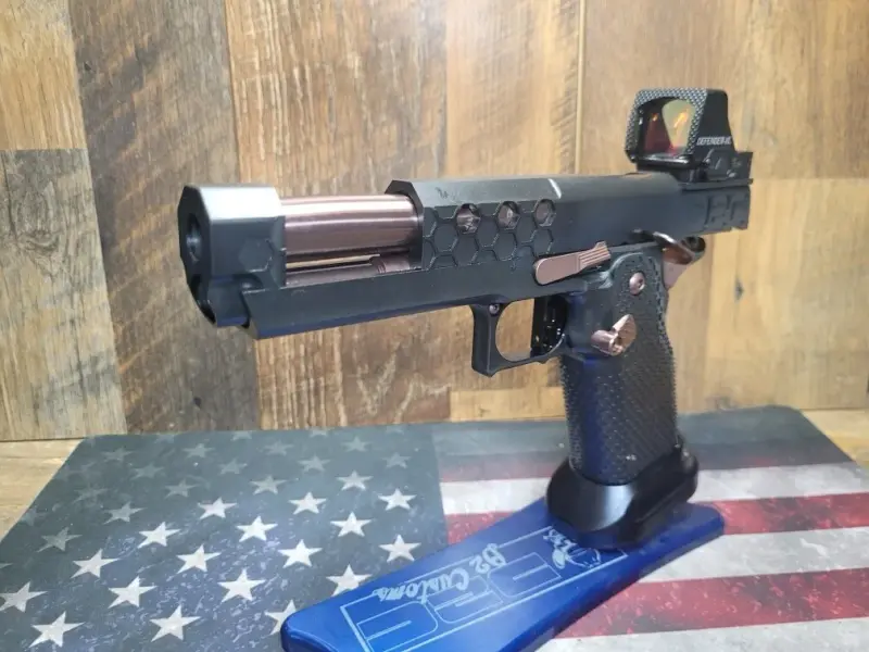 Slide racked back, exposing the bronze internals through the hex cuts